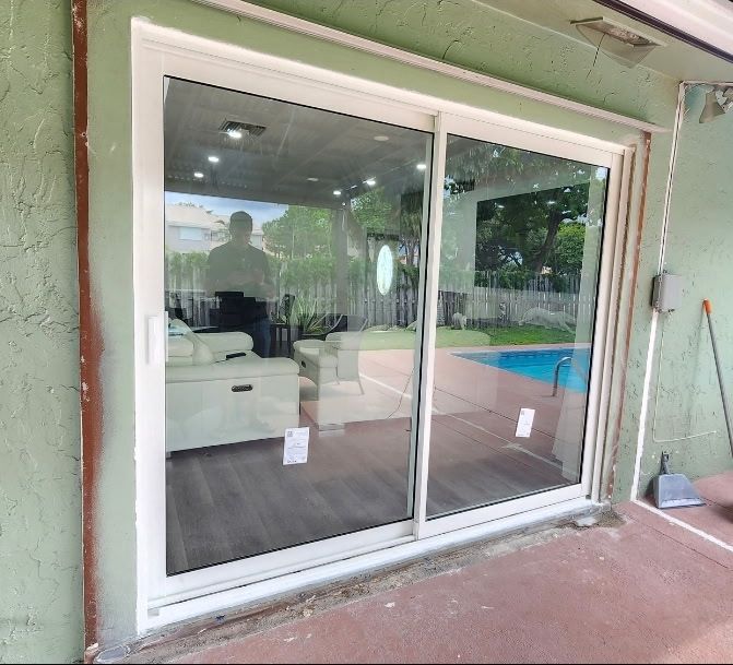 Newly installed white-frame impact sliding glass door on a pool patio