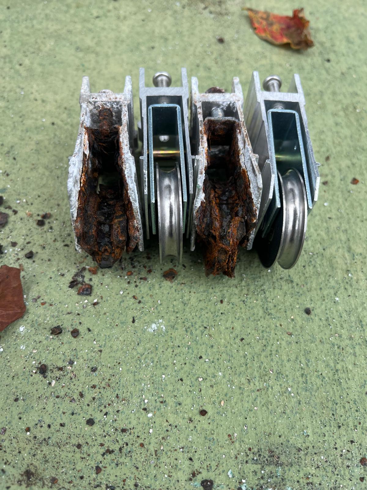 Corroded sliding glass door roller assemblies removed during a repair