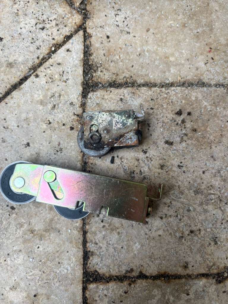 Rusted sliding door roller beside a new replacement roller